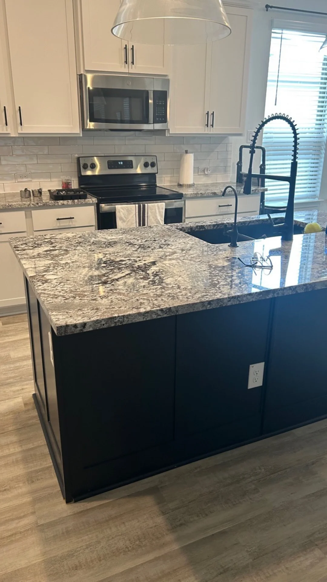 A clean dark kitchen island with granite countertops and modern fixtures in Georgetown, TX.