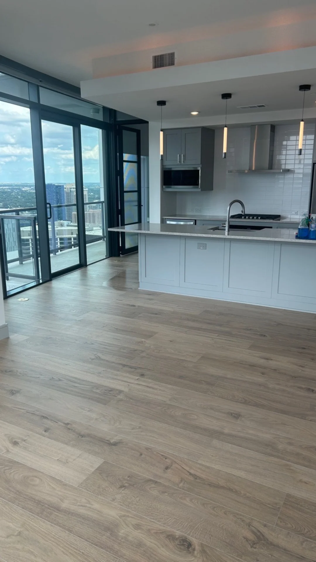 A modern apartment kitchen with clean laminate flooring and high-rise skyline views in Austin, TX.